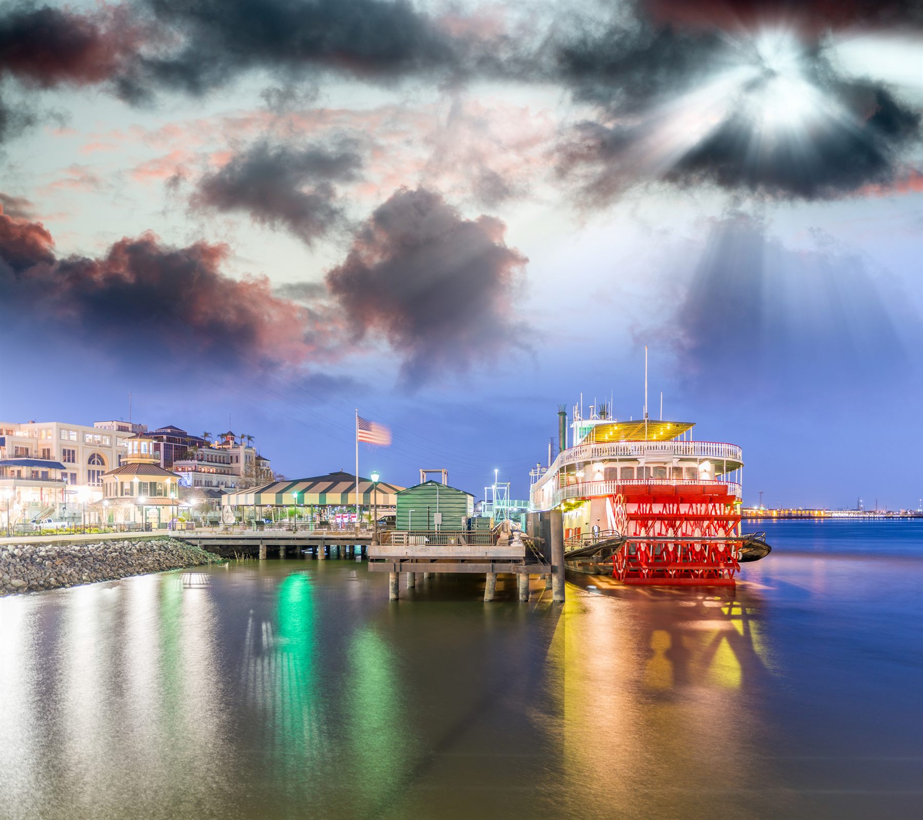 Red-wheeled steamboat docked at the New Orleans riverfront at dusk