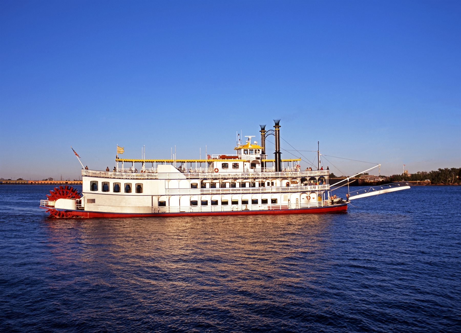 White sternwheeler with a red paddle wheel cruising on open water